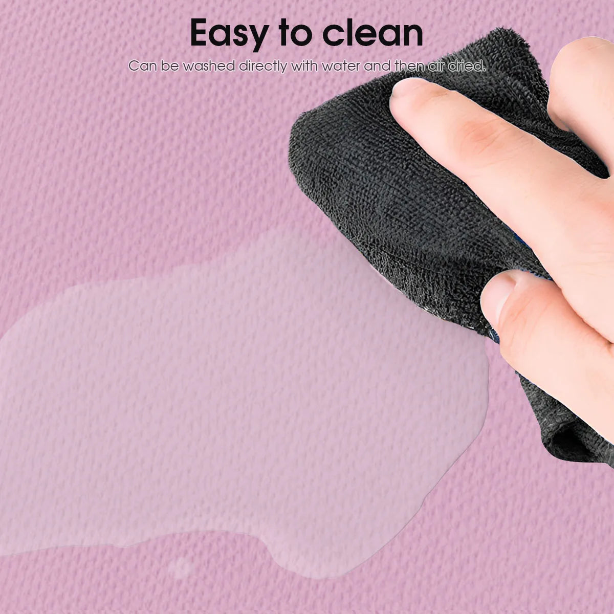 Hand wiping water spill on textured pink surface with black cloth, easy to clean mat
