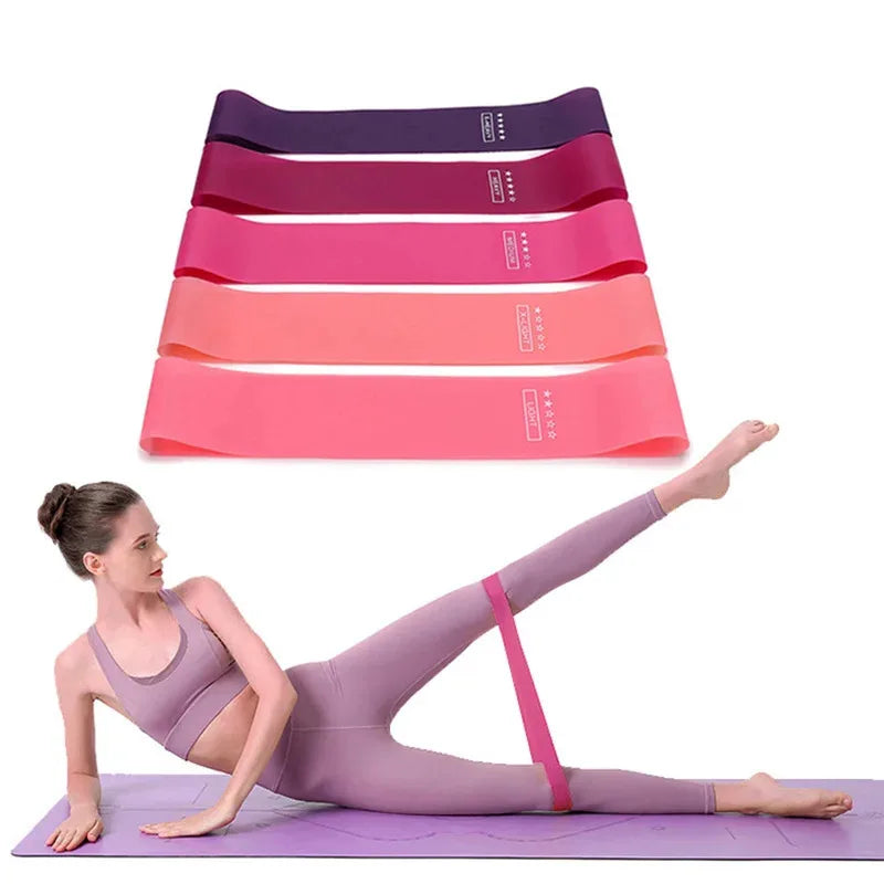Woman exercising with pink resistance band on yoga mat, five colorful resistance bands above her.